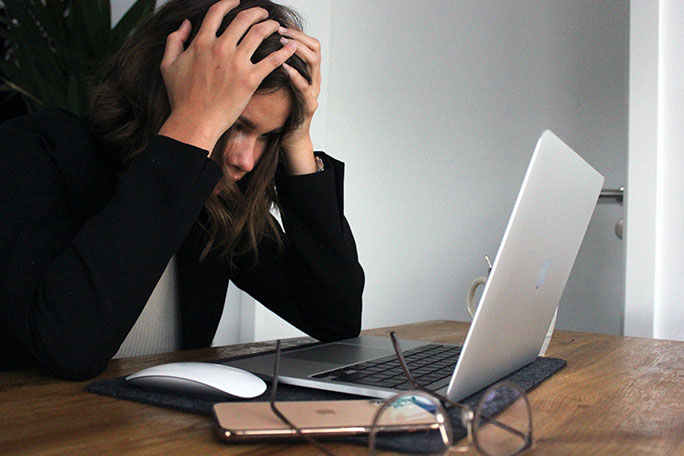 Photo of a frustrated woman in front of a computer. Image courtesy of Unsplash.